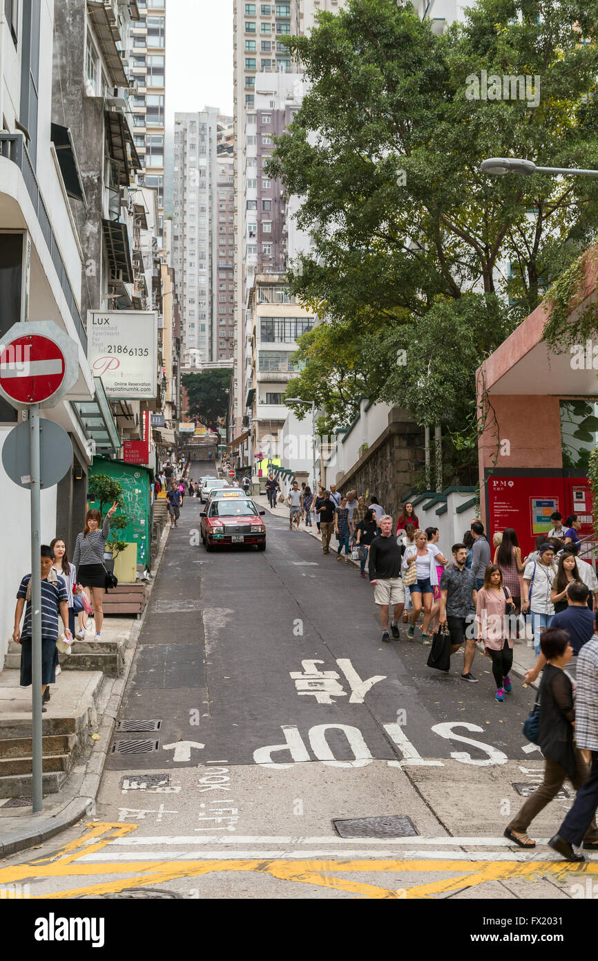 People and cars at a one-way street and high-rise buildings at the Mid-Levels in Central, Hong Kong, China. Stock Photo