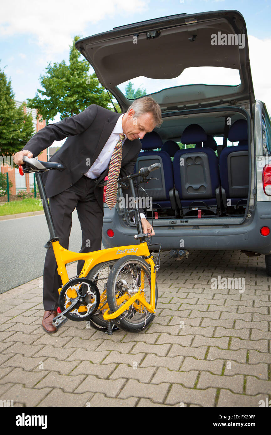Business man grabs his folding bike in the car trunk Stock Photo Alamy