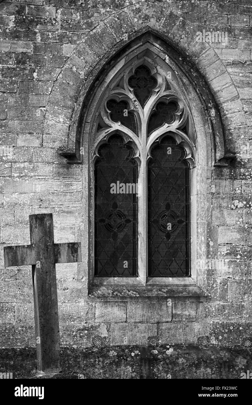 Grave stone next to a arched church window Black and white Stock Photo