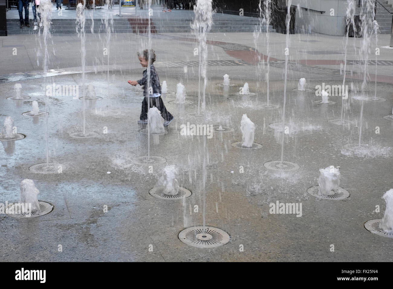 Child running through fountain in outdoor mall near Hollywood Walk of Fame, Los Angeles, California Stock Photo
