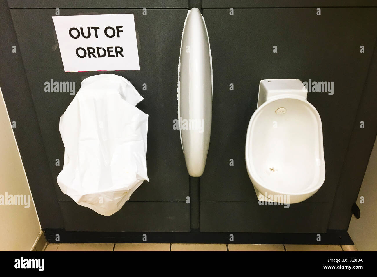 Out of Order sign on gents urinal covered in white plastic bag in