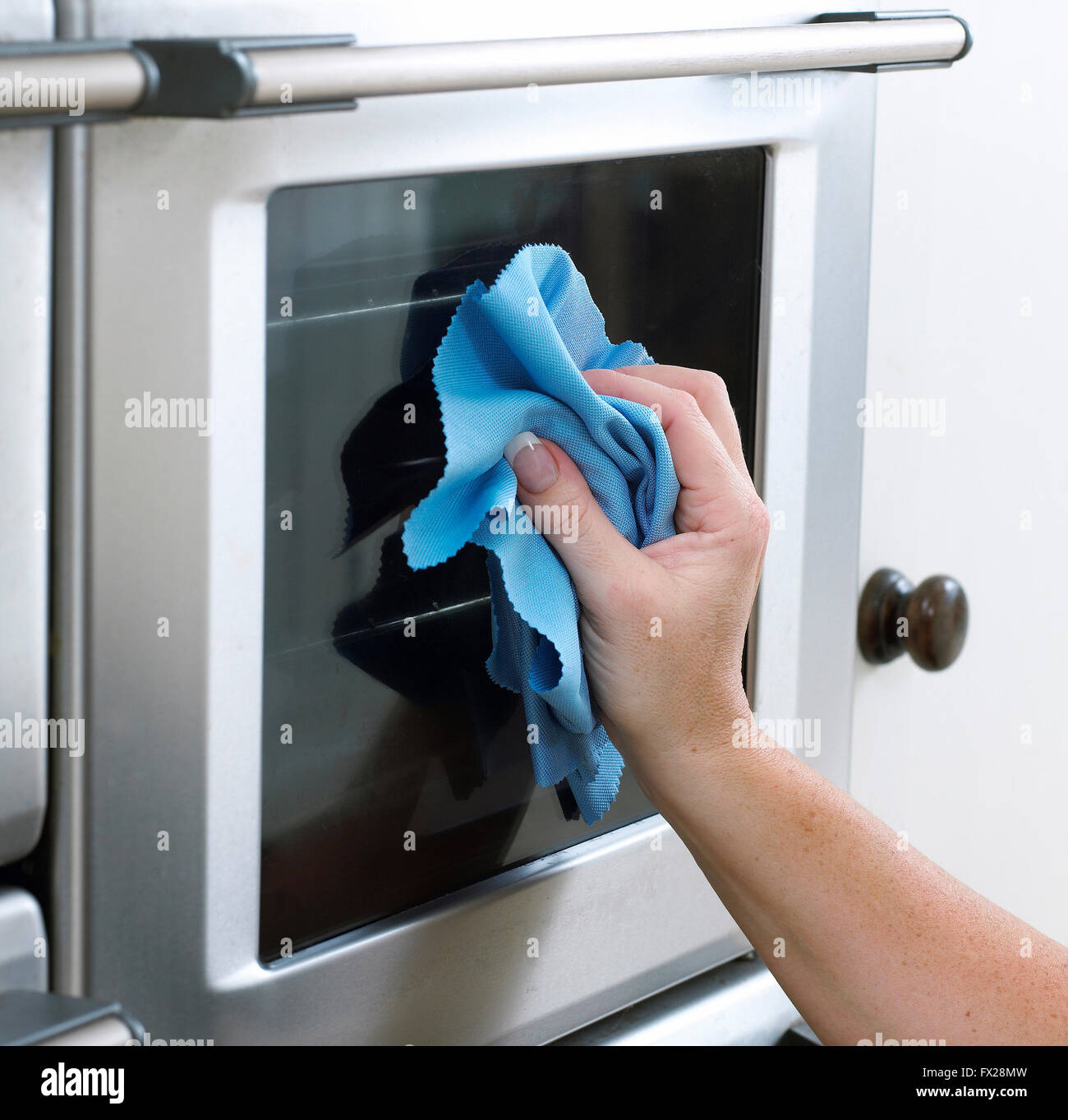 Woman cleaning a oven door with a microfiber cloth. Stock Photo