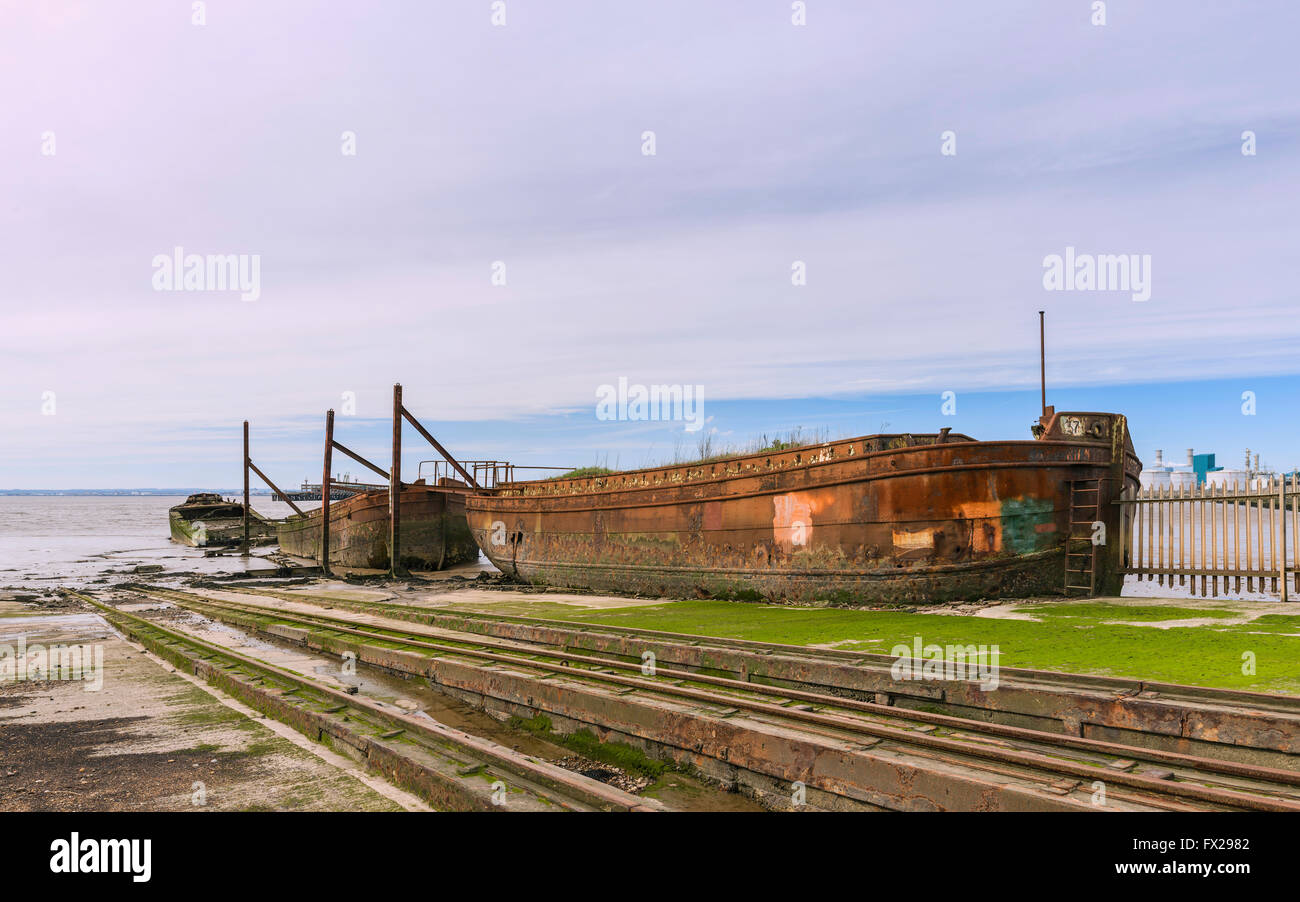 Disused ship yard with derelict iron ships and rusting rails for winching boats all flanked by mud banks of Humber estuary. Stock Photo