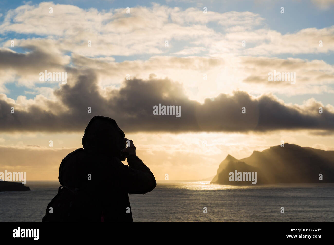 Photographer taking photos of sunrays over Tindhólmur Island at twilight from Vagar, Faroe Islands, Denmark in April - Faroes Tindholmur Island Stock Photo