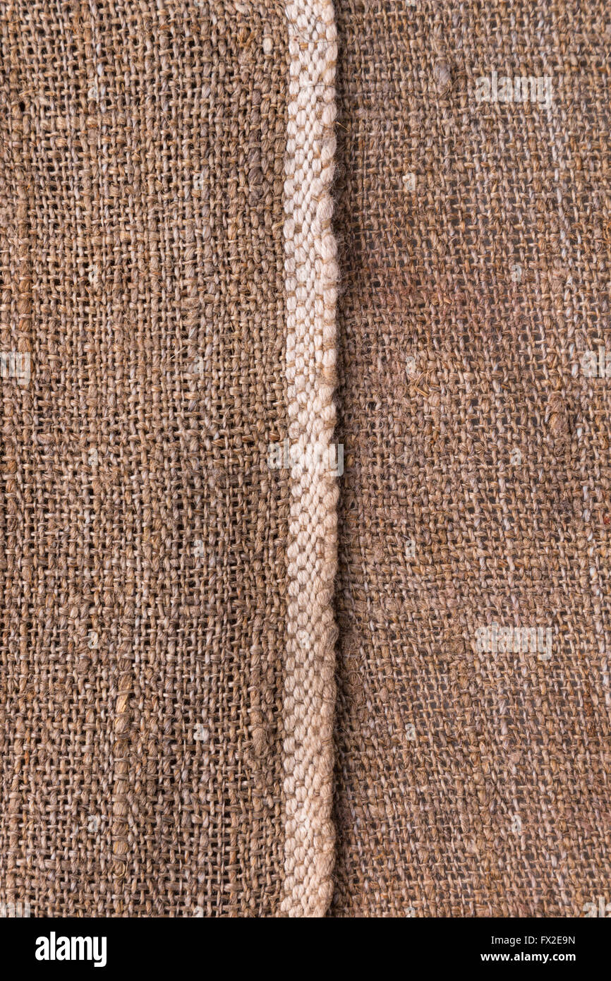Natural texture of burlap with a white stripe as a background, top view