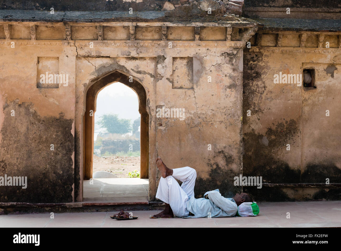 Indian man sleeping in ruins of monument Stock Photo