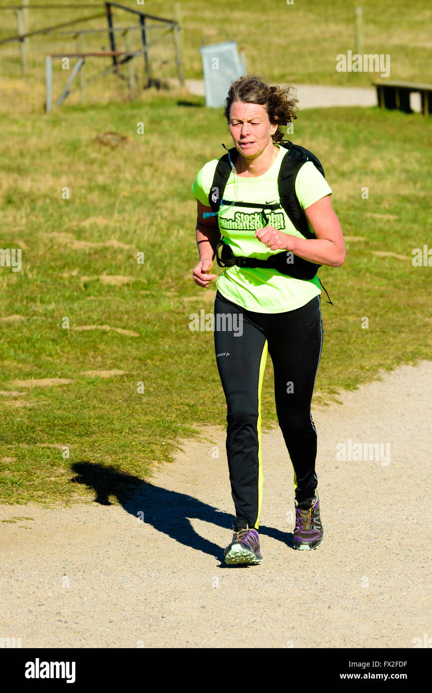 Kaseberga, Sweden - April 1, 2016: Female jogger running at gravel path surrounded by grass. Real people in everyday life in pub Stock Photo