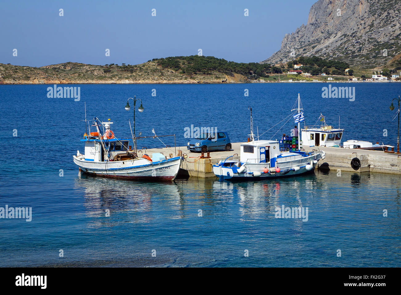 blue and white taxi-boat and concrete jetty with small car, Myrties, Kalymnos, Greece Stock Photo