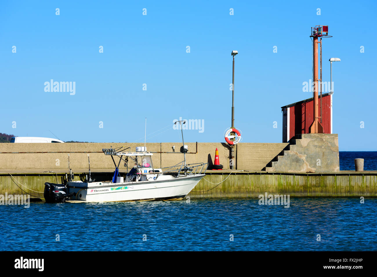 Kaseberga, Sweden - April 1, 2016: Beason motorboat moored at the stone pier in the marina. Navigational light at the end of the Stock Photo