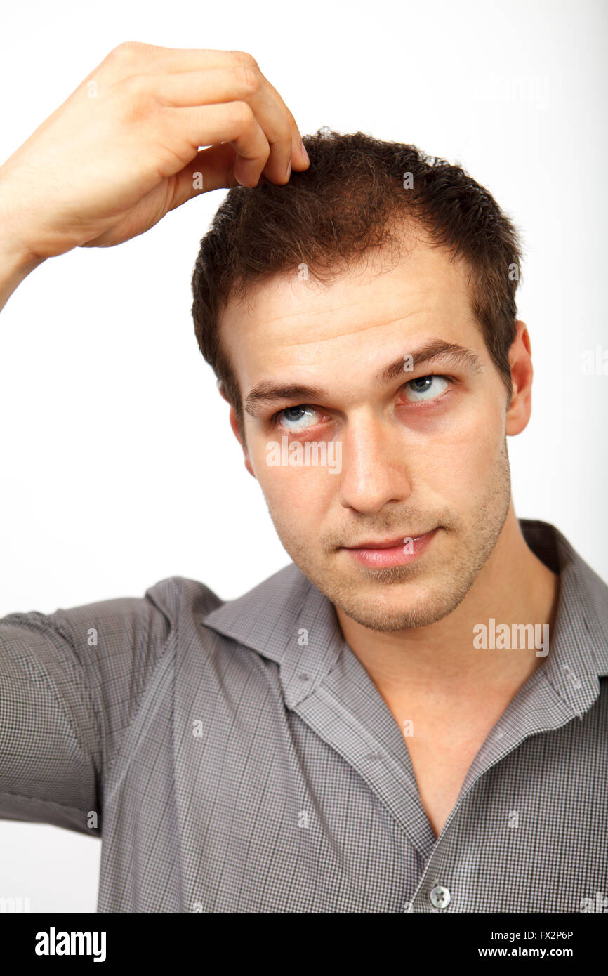 Hair loss problems. Man looking up at his balding head isolated in studio Stock Photo