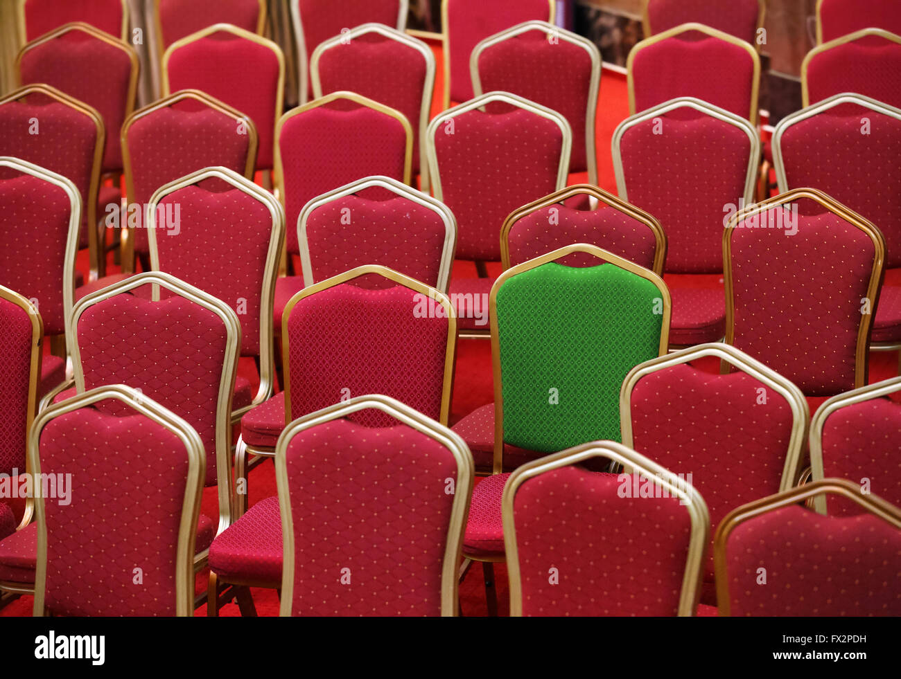 Diversity, different or unique concept - green chair in a group of red ones Stock Photo