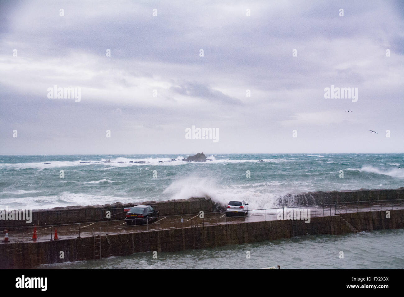 Mousehole, Cornwall, UK. 10th April 2016. UK Weather. The latest storm to hit Cornwall with 65mph winds and a high spring tide swamp cars on Mousehole Harbour Wall, almost pushing one of them into the harbour itself. Credit:  Simon Maycock/Alamy Live News Stock Photo