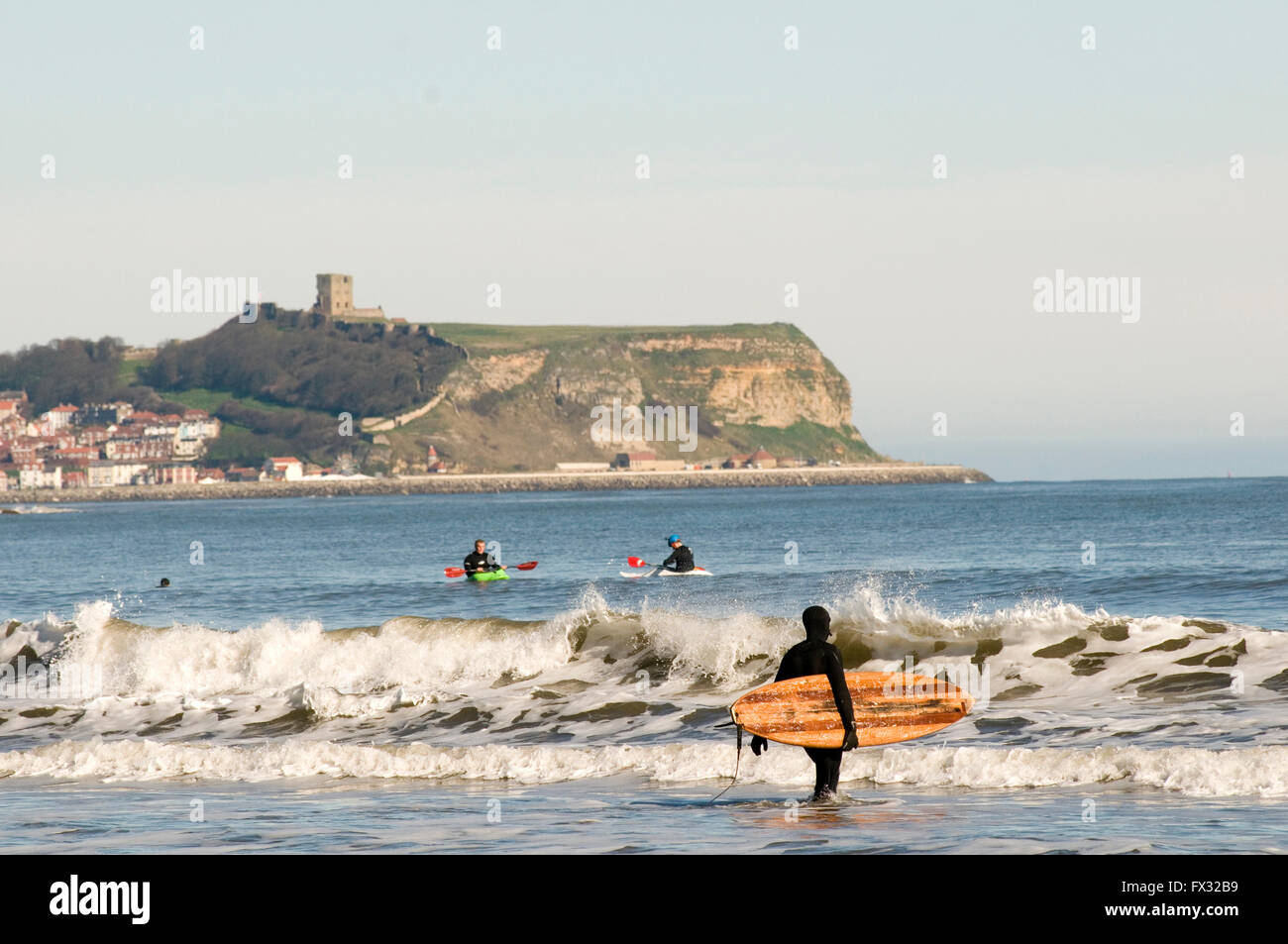 Cayton Bay, Scarborough, UK. 10th April, 2016. Nice Weather at Scarborough; people surfing in the north Sea; at Cayton Bay; Scarborough castle in the background; warm sunny weather story stories unseasonably unseasonably sun shine Credit:  picturesbyrob/Alamy Live News Stock Photo