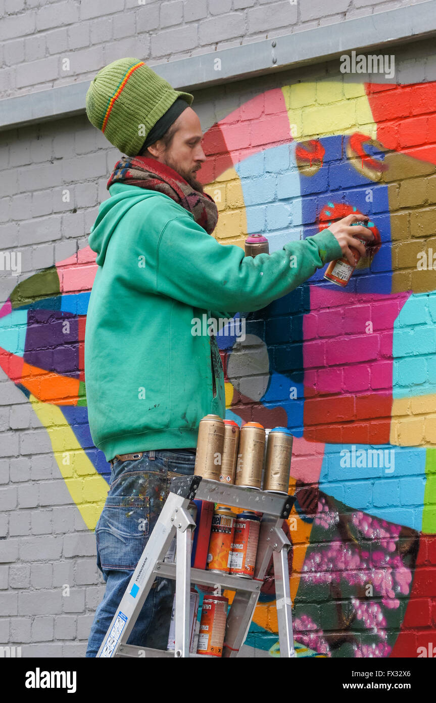 A graffiti artist spray painting a colourful piece of work in London, England United Kingdom UK