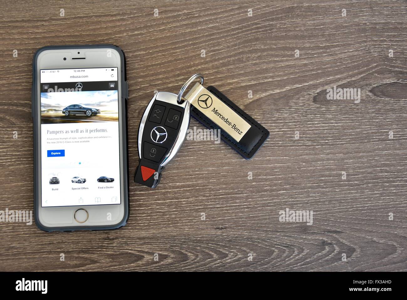 An Apple iPhone displaying the Mercedes-Benz web page while laying next to a Mercedes-Benz key fob Stock Photo