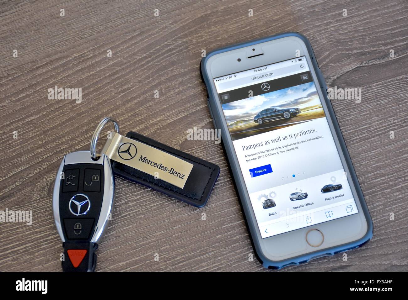 An Apple iPhone displaying the Mercedes-Benz web page while laying next to a Mercedes-Benz key fob Stock Photo