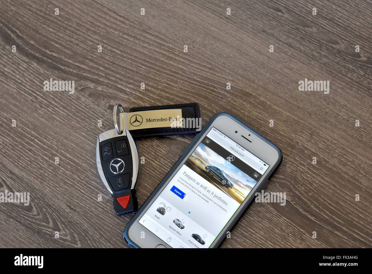 An Apple iPhone displaying the Mercedes-Benz web page while laying next to a Mercedes-Benz key fob Stock Photo