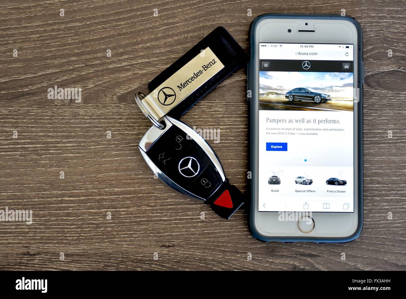 An Apple iPhone displaying the Mercedes-Benz web page while laying next to a Mercedes-Benz key fob Stock Photo