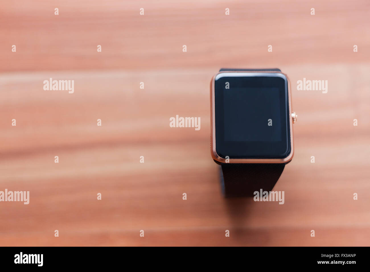 Smart wrist watch laying on the wooden background. Elegant new technology that lets you always stay connected Stock Photo