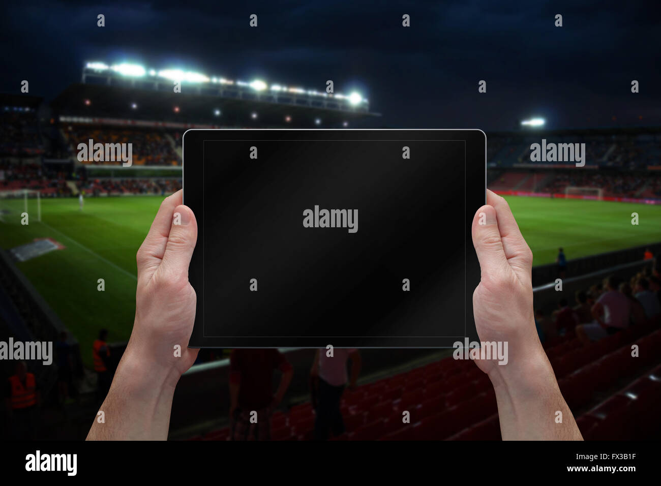 Man holding tablet with blank screen on soccer game. Stadium in background. Stock Photo