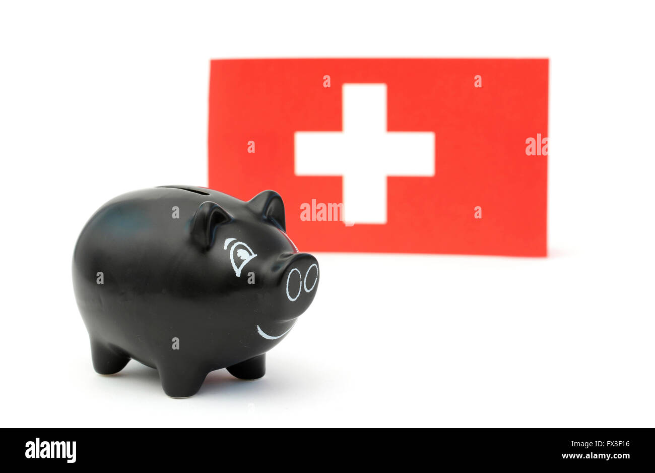 A black piggy bank in front of a Swiss flag Stock Photo