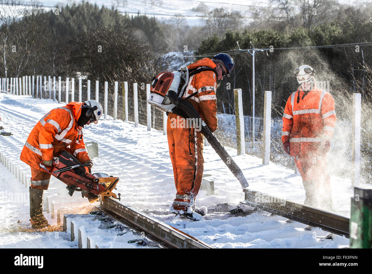 Construction workers blowing snow off and cutting new rail line Borders