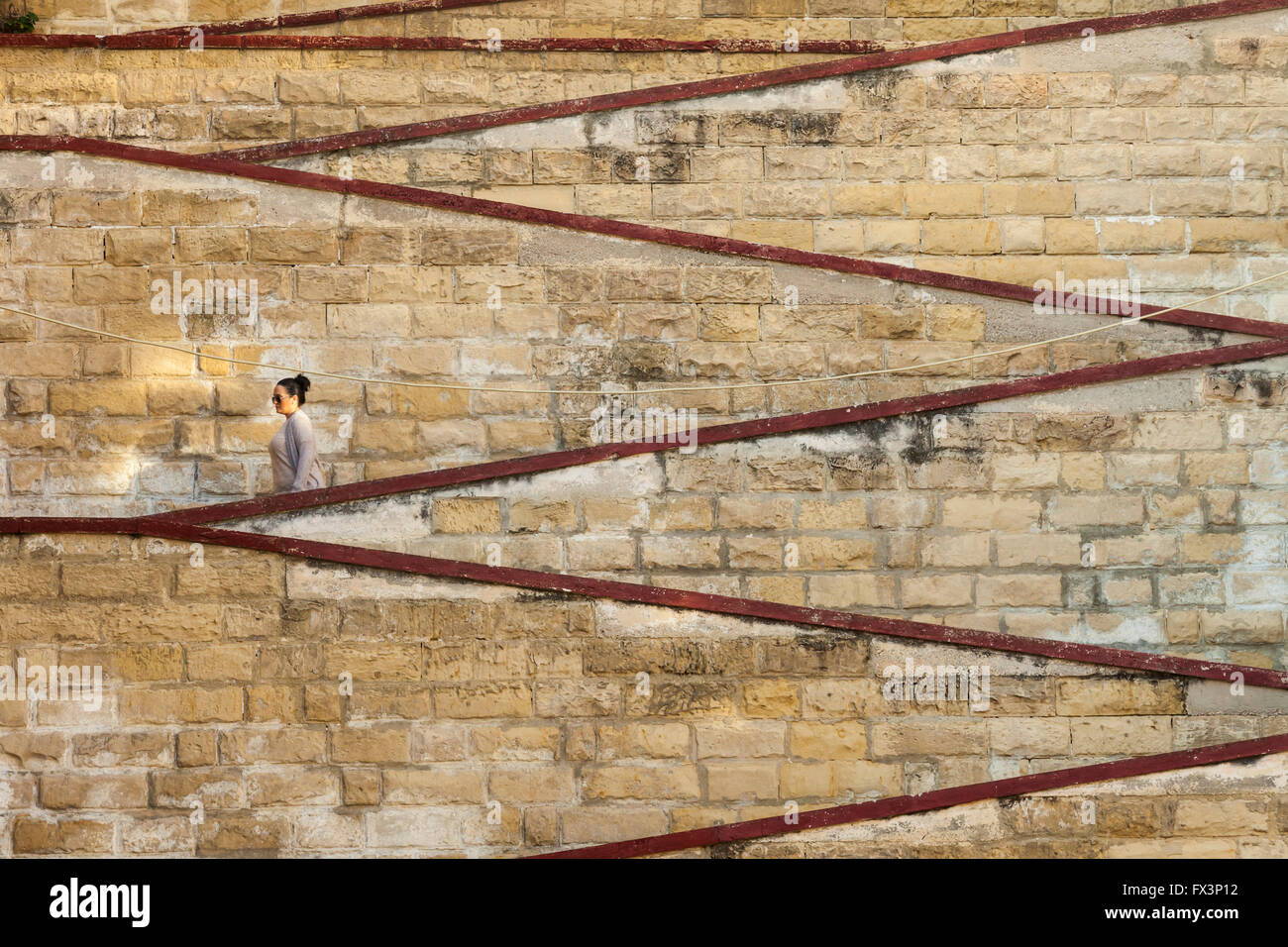 Woman walking down a zigzagging stairs passage in Senglea, Malta. Stock Photo