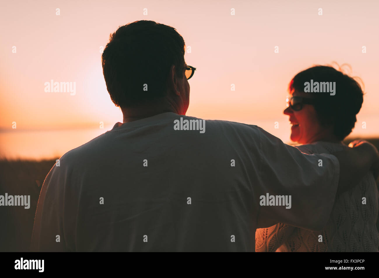 Back view a married couple a silhouette sitting on a bench. Stock Photo