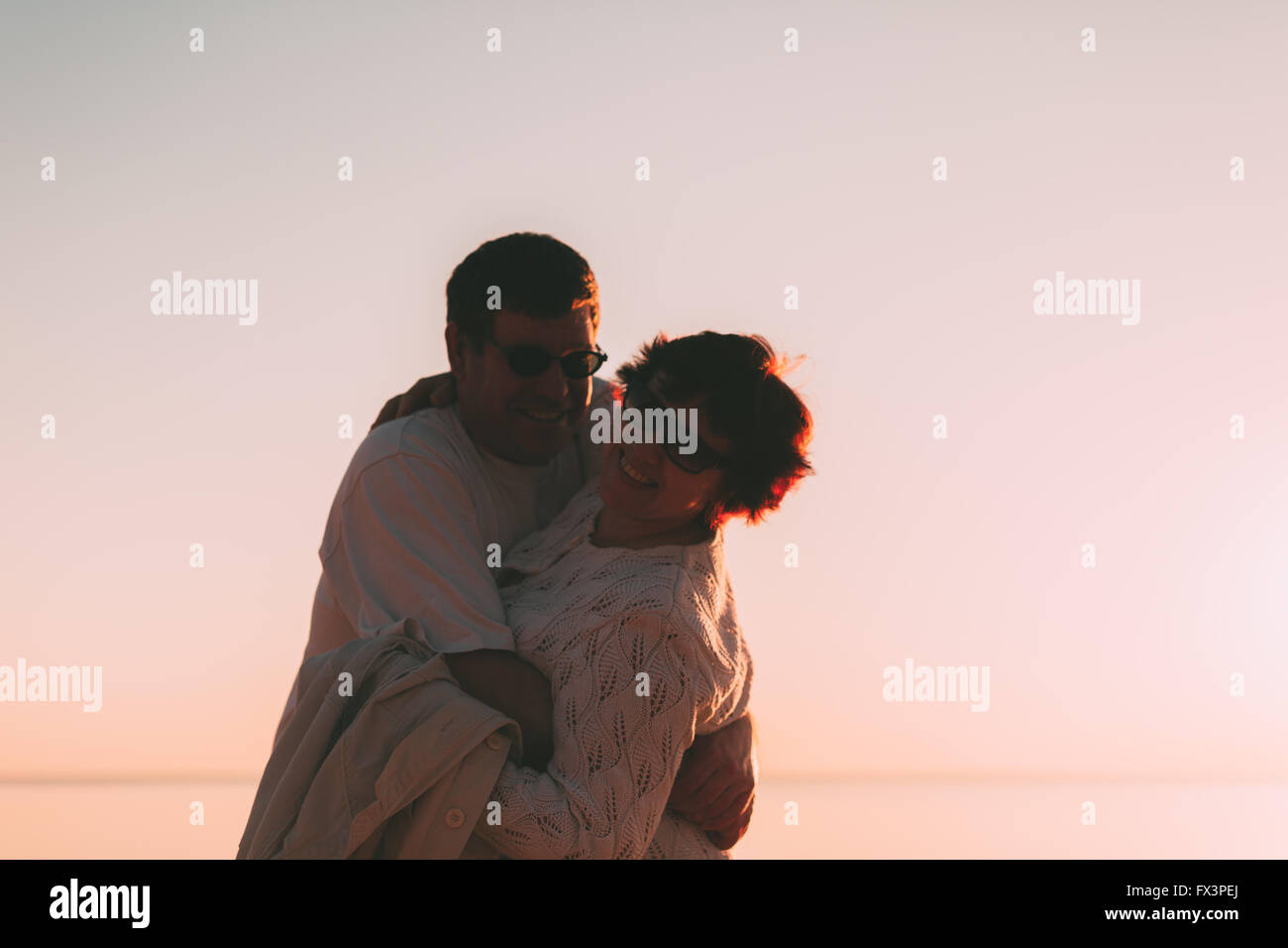 Adult couple embracing at sunset and sea. Stock Photo