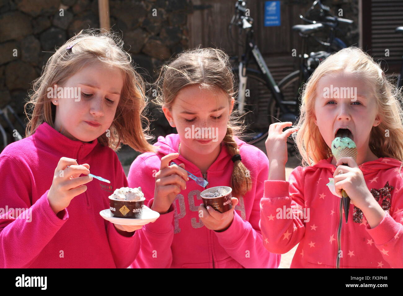 Children enjoying eating ice cream cone on a warm sunny day, three girls enjoying icecream, best life, contentment, happiness is, satisfaction Stock Photo