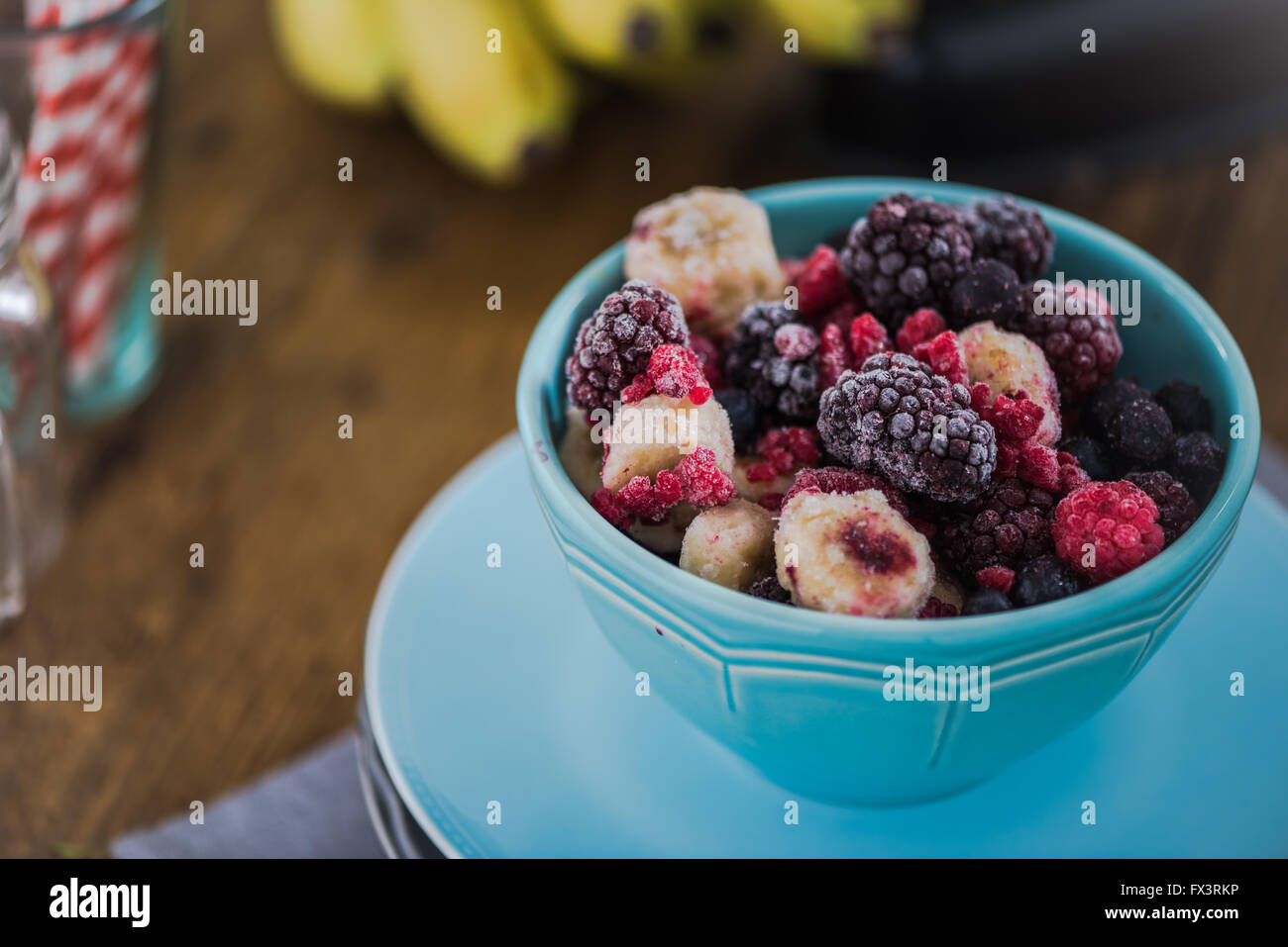 Frozen berry fruits, smoothie ingredients. In vibrant blue bowl, on wooden table Stock Photo Alamy