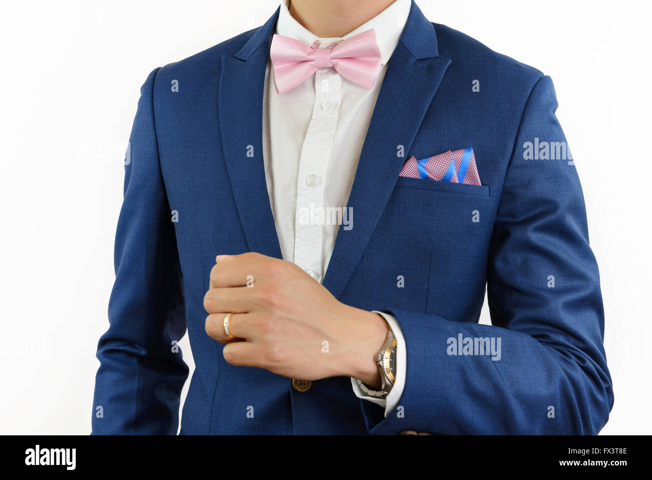 Man in blue suit with pink bow tie, flower brooch, and pink blue strip pocket square, close up Stock Photo