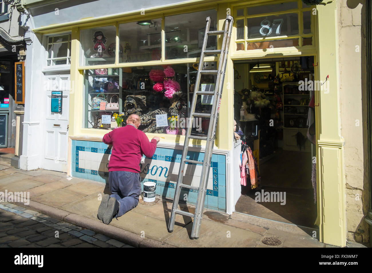 A decorator painting the exterior of a shop in Church Street Whitby