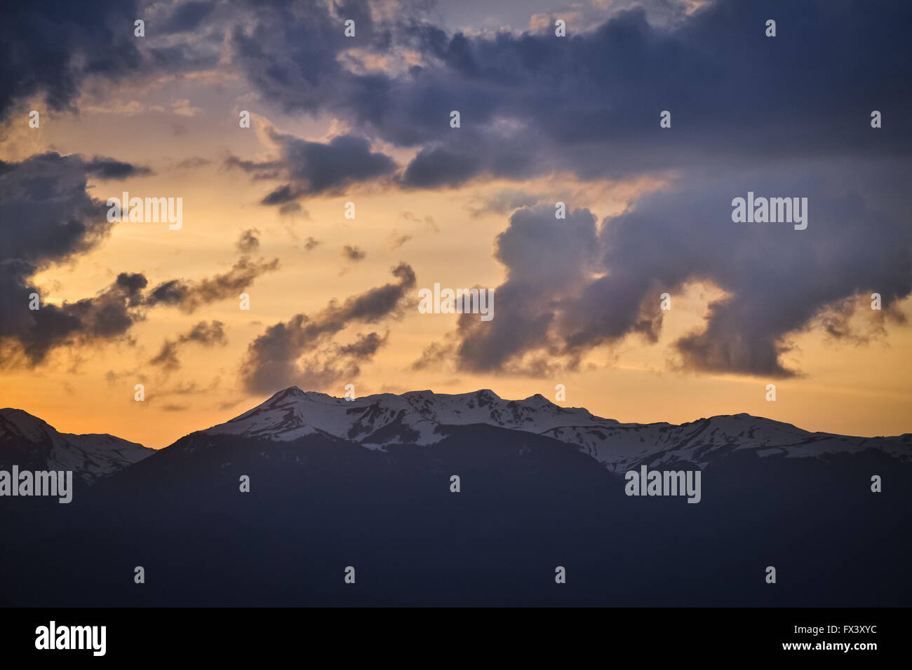 Snowy peak of the mountain and cloudy sky during the sunset Stock Photo