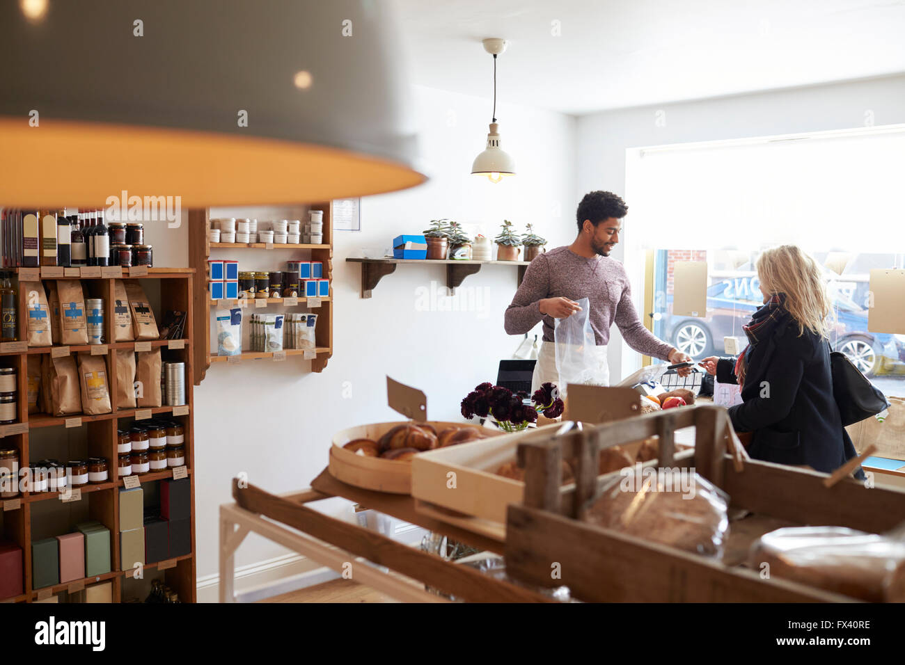 Male Sales Assistant Serving Female Customer In Delicatessen Stock