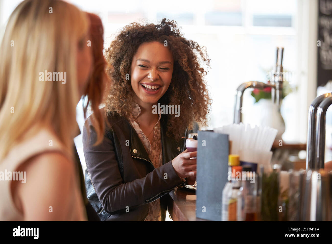 Group Of Female Friends Enjoying Drink In Cocktail Bar Stock Photo
