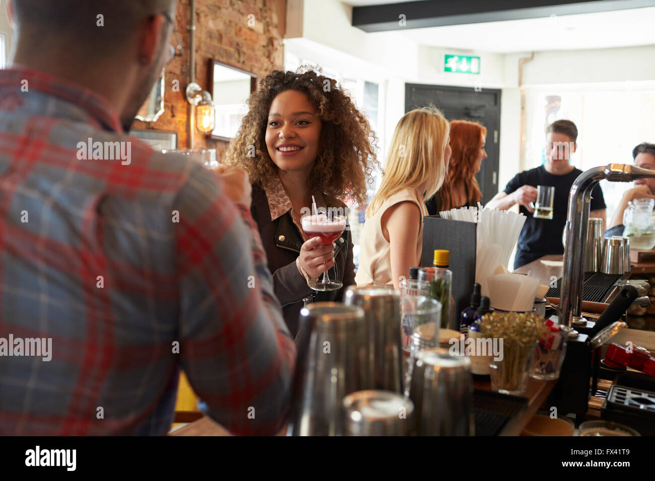 Young Couple Enjoying Drink In Busy Cocktail Bar Stock Photo