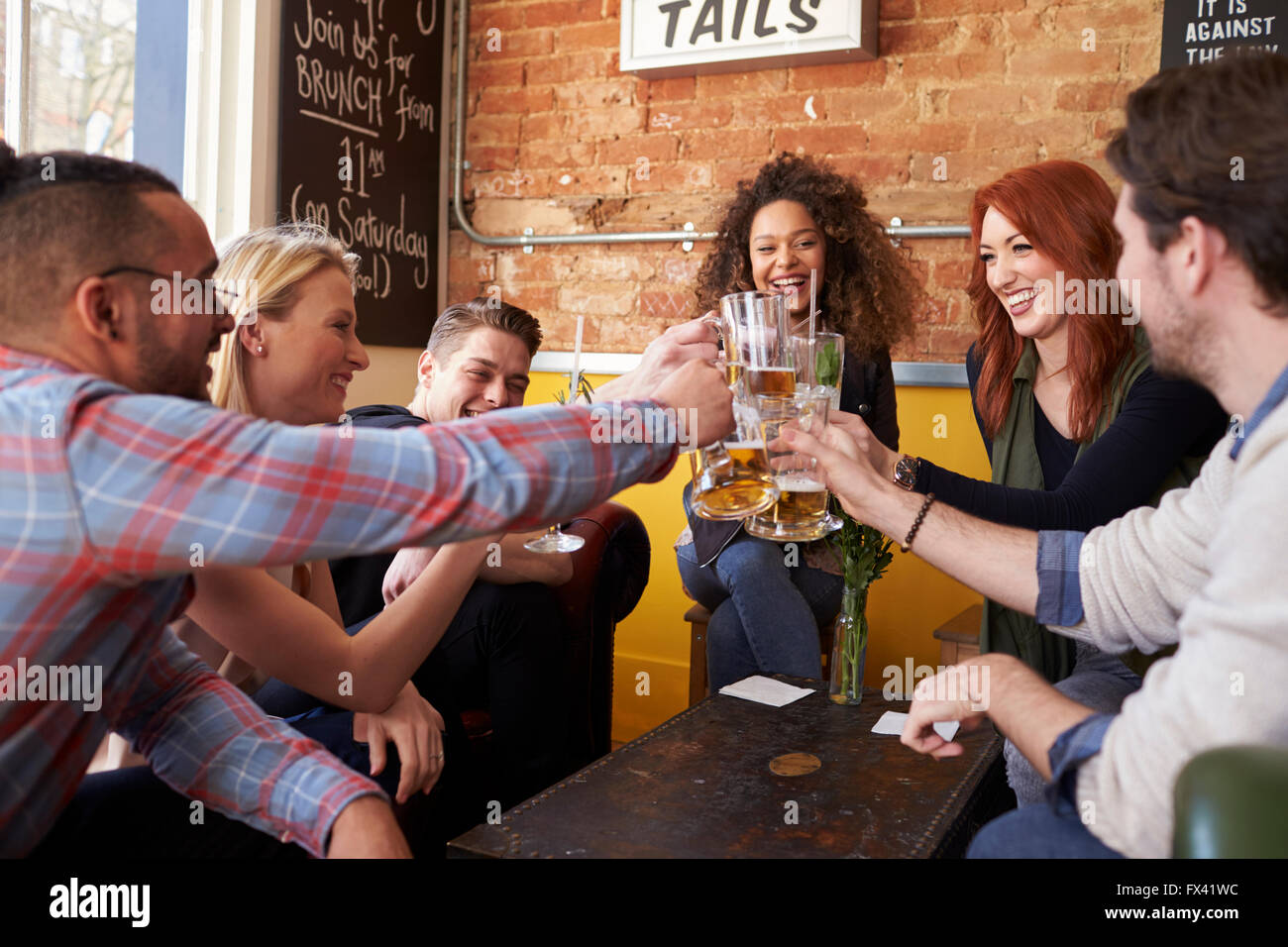 Group Of Friends Enjoying Drink In Bar Sitting On Sofa Stock Photo