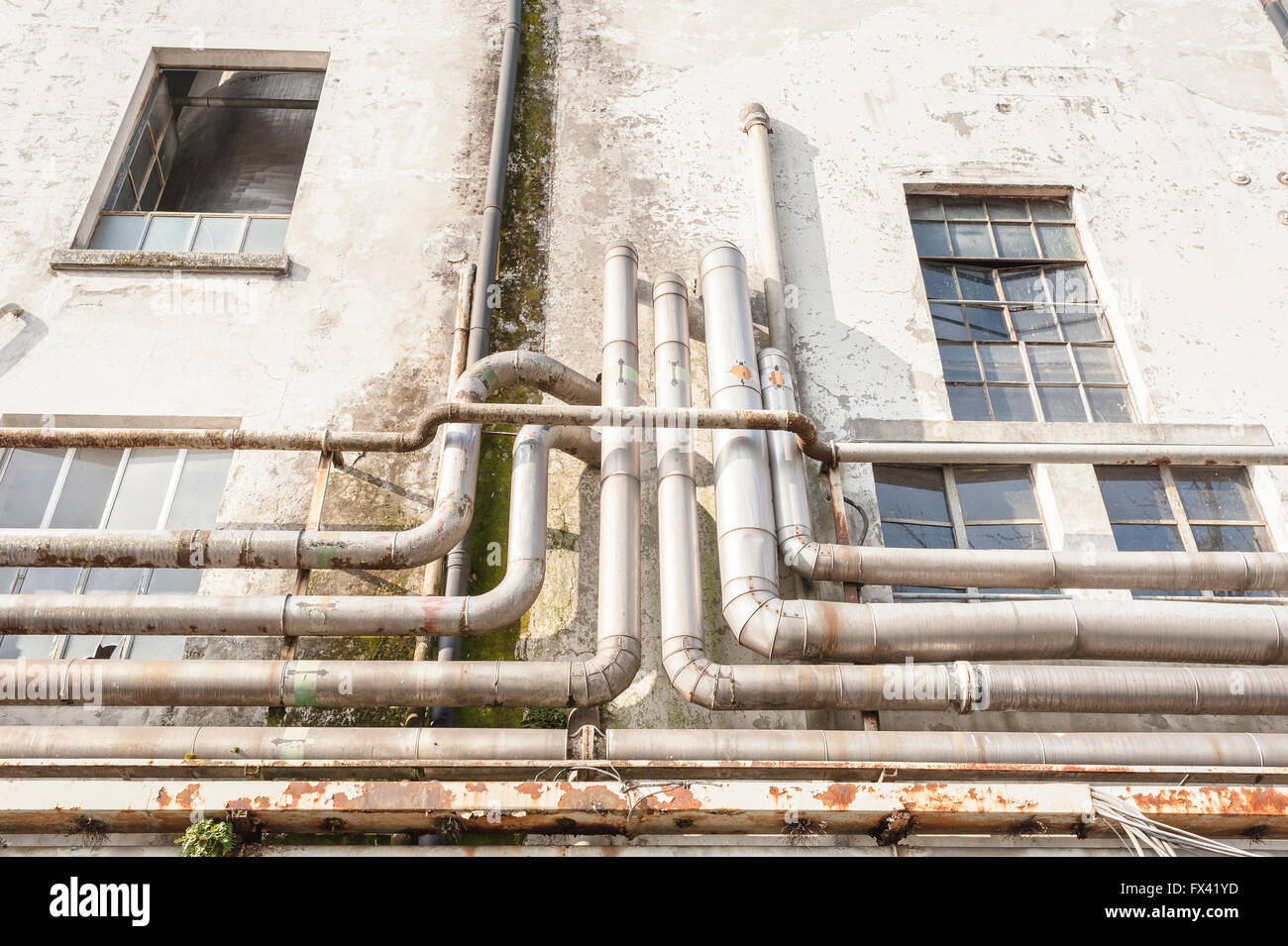 Old pipes on the wall outside of an old abandoned factory. Stock Photo