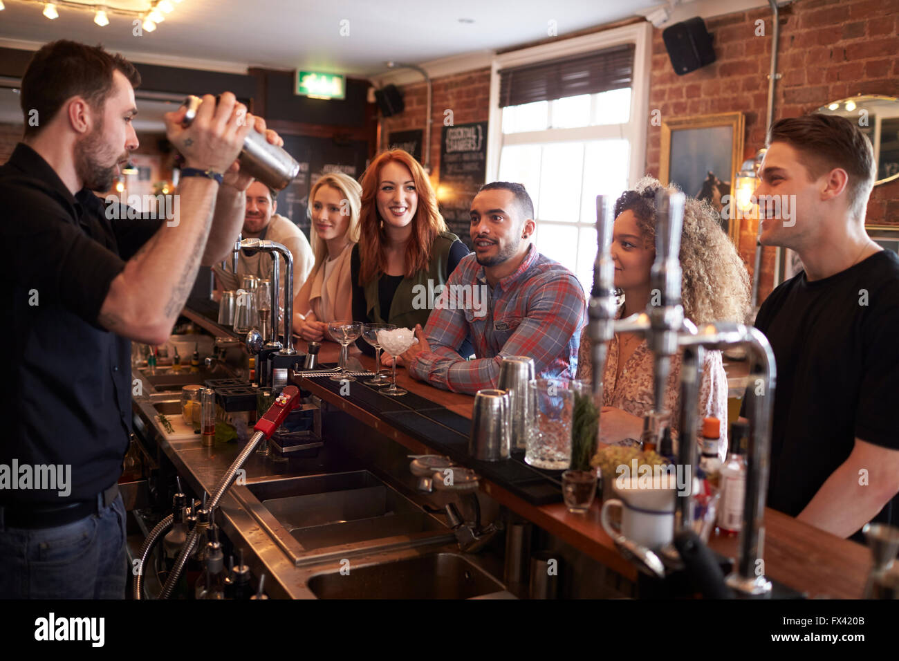 Bartender Giving Cocktail Making Lesson to Friends In Bar Stock Photo