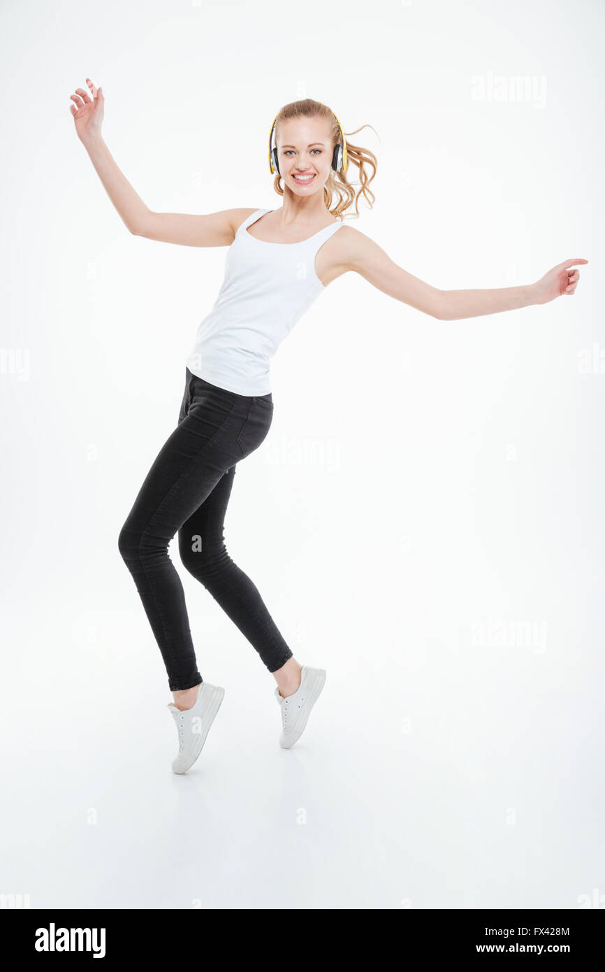 Happy cute young woman listening to music using headphones and dancing ...