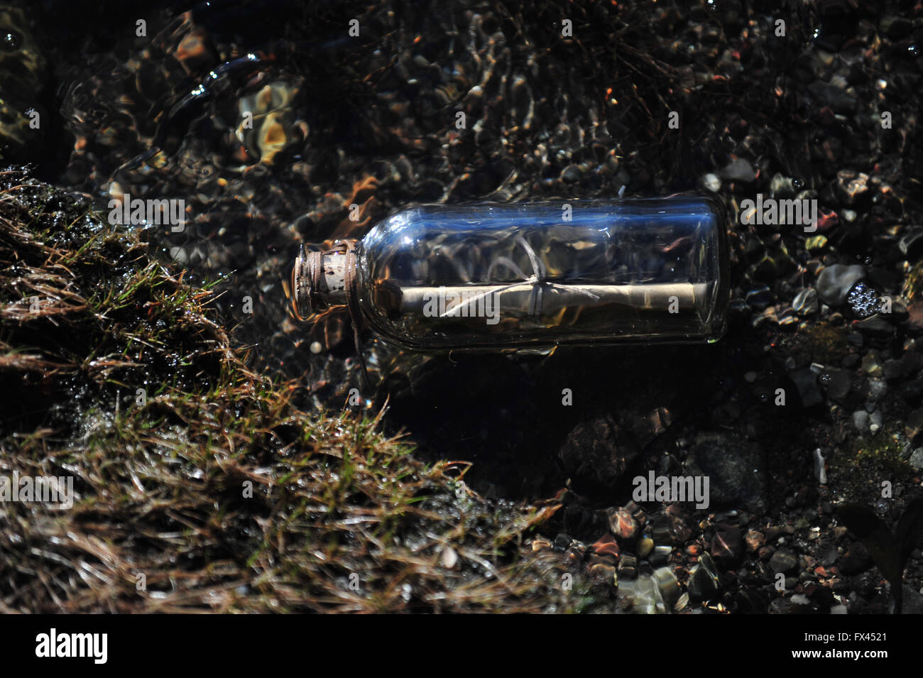 Message in a bottle floating in water. Stock Photo