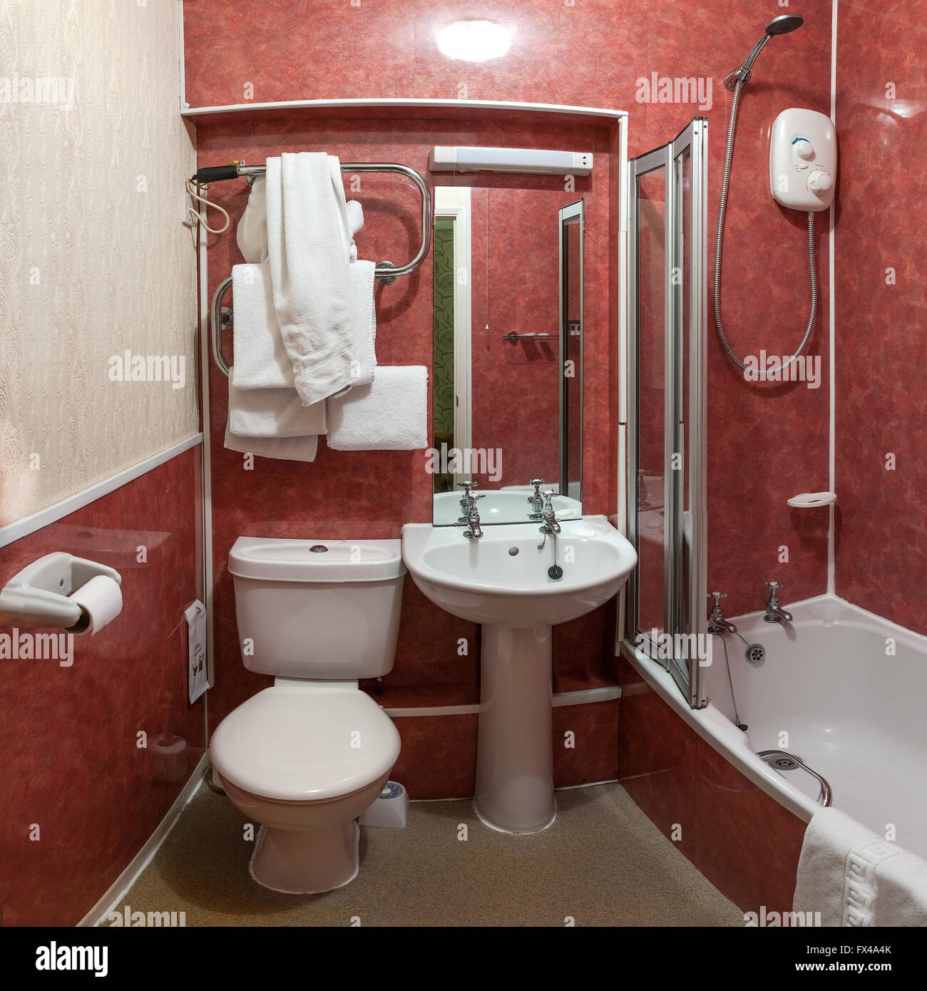 Hotel bathroom showing toilet, washbasin, bath and shower with towels ready. Stock Photo
