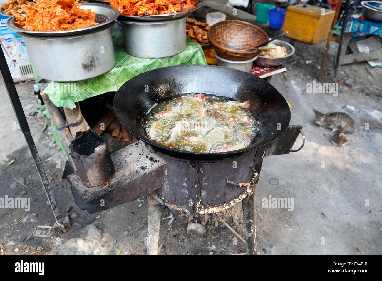 Frying fish by cooking in boiling oil at a local street stall by U Bein