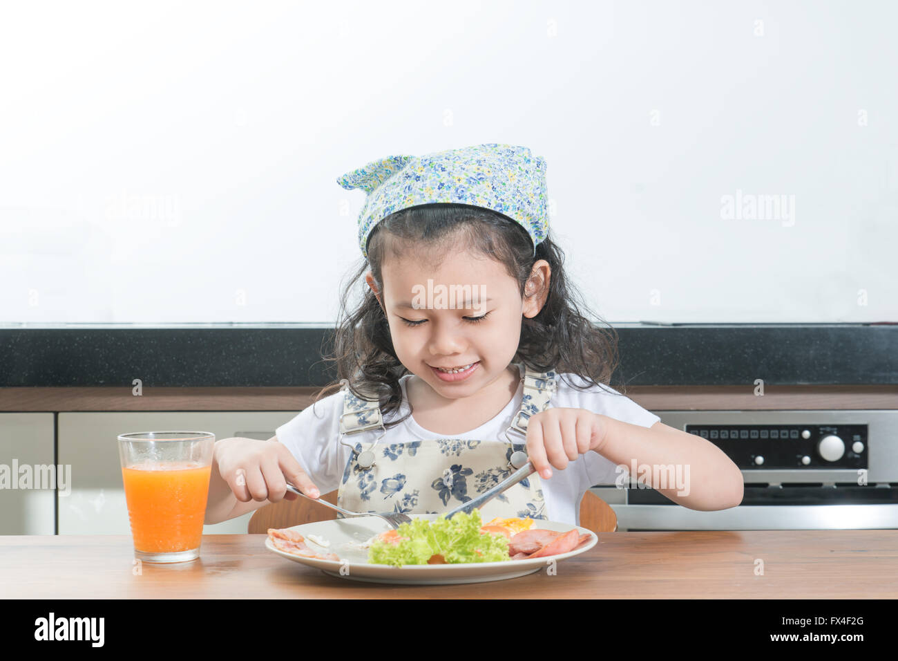 family, children and happy people concept - Asian girl child eating american breakfast in home Stock Photo