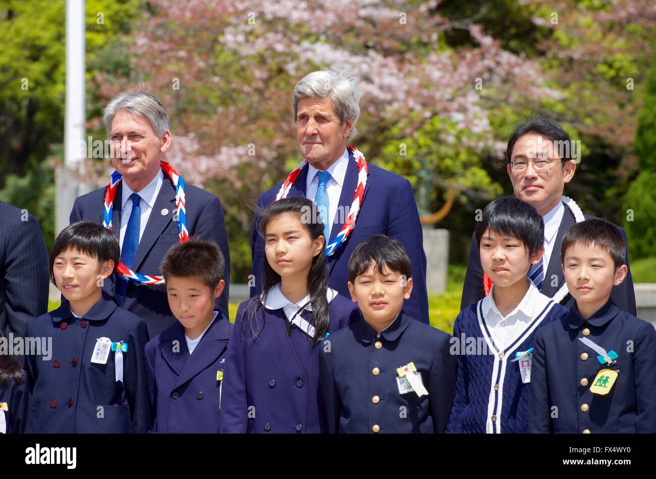 Hiroshima, Japan. 11th Apr, 2016. U.S Secretary of State John Kerry, centers, British Foreign Secretary Philip Hammond and Japanese Foreign Minister Fumio Kishida pose with school children after a wreath laying ceremony during a visit the Hiroshima Peace Memorial during a break from meetings April 11, 2016 in Hiroshima, Japan. Kerry is the highest ranking U.S official to visit the site of the atomic bomb blast since World War II ended. Credit:  Planetpix/Alamy Live News Stock Photo