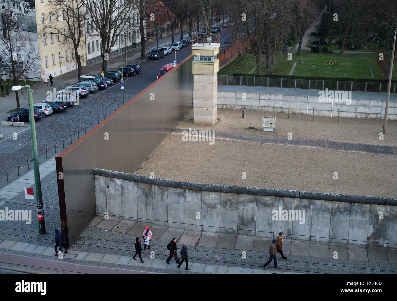 People walk next to a remaining part of the Berlin Wall at the Berlin Wall Memorial in Berlin at Bernauer Straße on December, 30, 2015. The photo was taken from the visitors platform of the Berlin Wall Memorial. Photo: Wolfram Steinberg/dpa Stock Photo