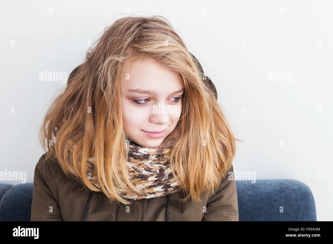Close up portrait of beautiful blond Caucasian teenage girl in warm scarf over white wall background Stock Photo