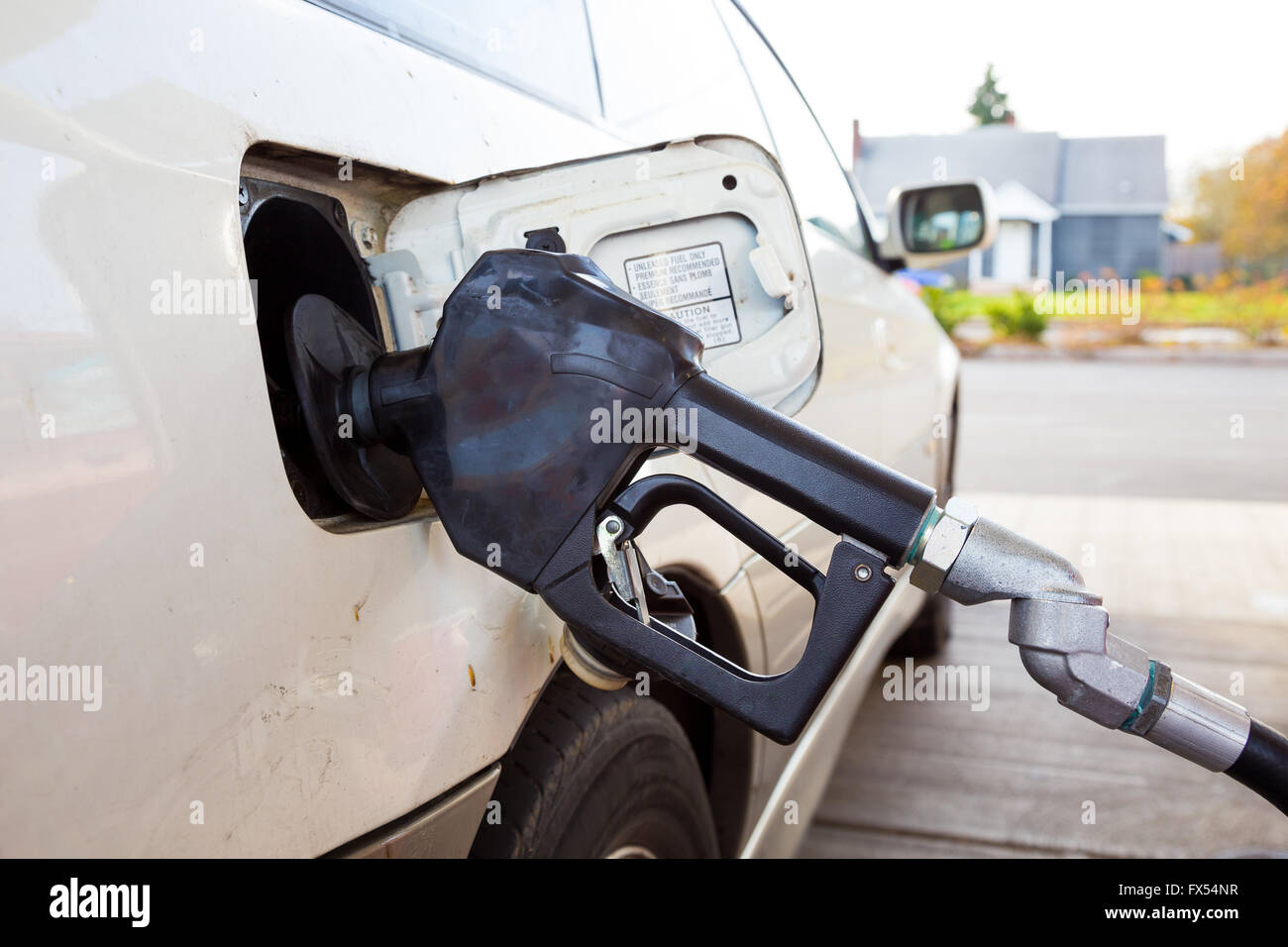 A gas pump is pumping gas into this car at the gas station while