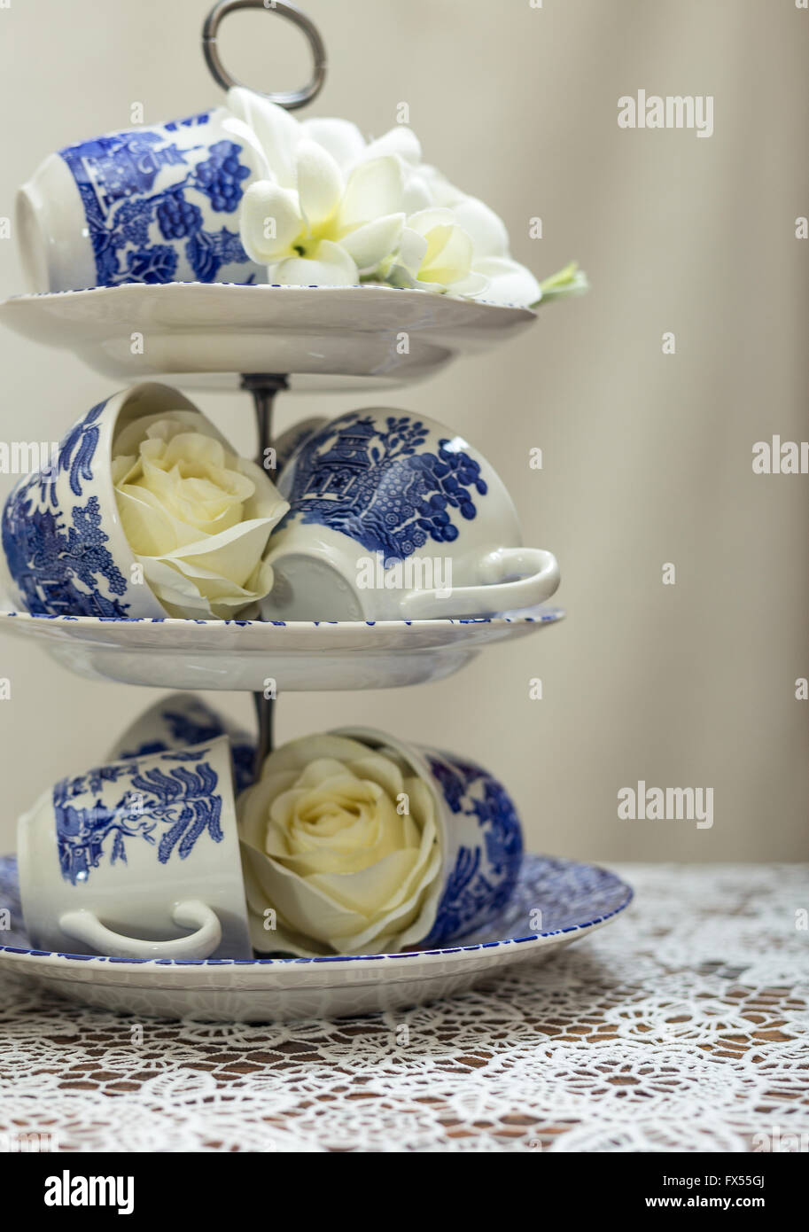 Blue and white willow pattern cake stand and cups on lace cloth for wedding  afternoon tea with roses and bouquet Stock Photo - Alamy